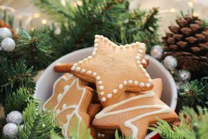 Имбирное печенье в форме звезд в белой посуде и вокруг елочный новогодний венок
