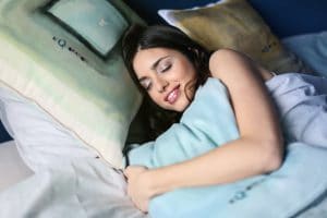 Девушка спит на подушках и улыбается во сне
