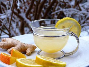 Имбирный чай в стеклянной чашке с дольками лимона и апельсина на фоне снежного пейзажа