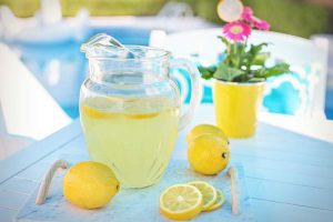 Лимонад в графине и на подносе с лимонами по бокам