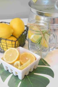 лимонная вода с цитрусами в стеклянной банке и фарфоровой тарелке