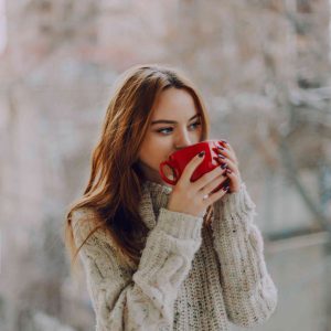 девушка в свитере пьет чай из кружки