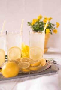 лимонный напиток в стаканах с трубочками и льдом