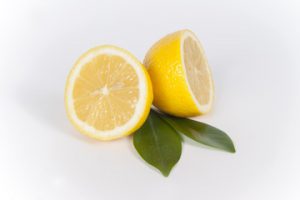 половинки лимона с зелеными листиками на белом фоне