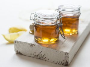 лимон и продукт пчеловодства в двух стеклянных банках
