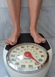 девушка стоит на весах и измеряет вес
