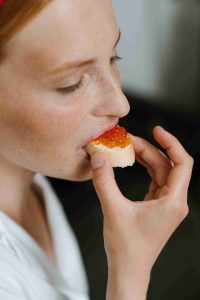 девушка ест бутерброд с красной икрой