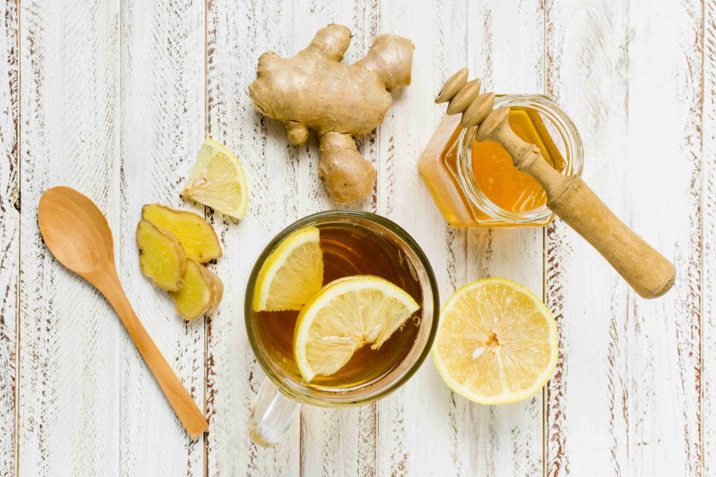 Имбирь лимон и мед на фоне деревянного белого фона, и чай в стеклянном стакане