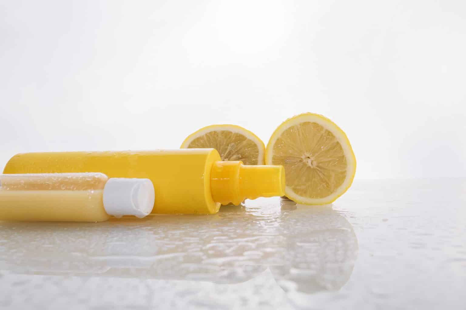 лимонный сок и лимон вместе с желтой бутылкой пульверизатора на белом фоне