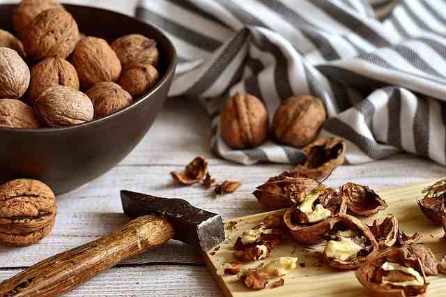 грецкие орехи, расколотые молотком, на деревянной доске и в миске